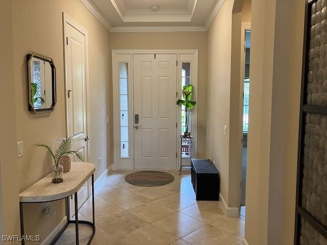 entryway with a tray ceiling and crown molding