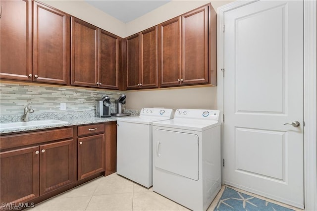 laundry room featuring light tile patterned floors, independent washer and dryer, and a sink