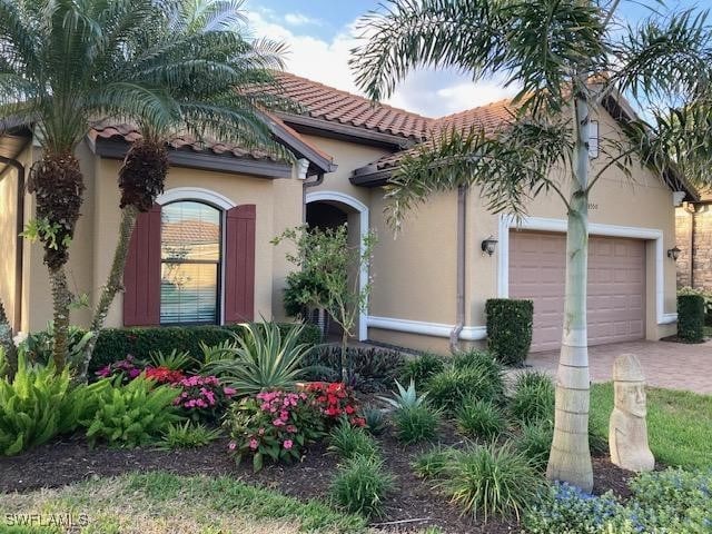 mediterranean / spanish house with stucco siding, decorative driveway, an attached garage, and a tiled roof