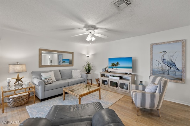 living room with a textured ceiling, hardwood / wood-style flooring, and ceiling fan