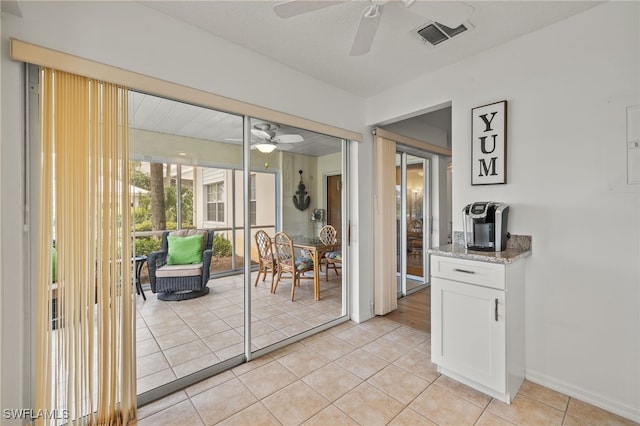 doorway featuring ceiling fan and light tile patterned floors