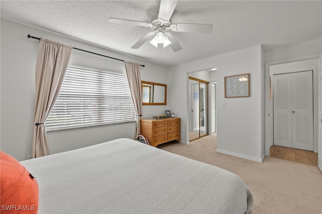 bedroom featuring a textured ceiling, light carpet, and ceiling fan