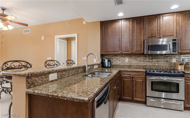 kitchen with a kitchen breakfast bar, kitchen peninsula, appliances with stainless steel finishes, and sink