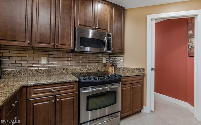 kitchen featuring appliances with stainless steel finishes, decorative backsplash, dark stone countertops, and dark brown cabinets