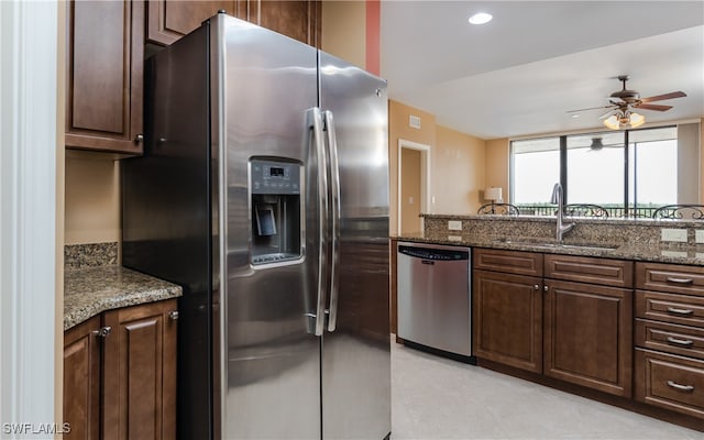 kitchen featuring ceiling fan, dark brown cabinetry, sink, stone countertops, and stainless steel appliances