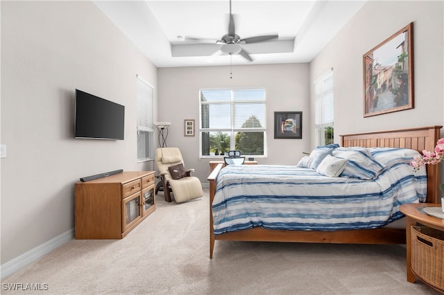 bedroom with a tray ceiling, light carpet, and ceiling fan