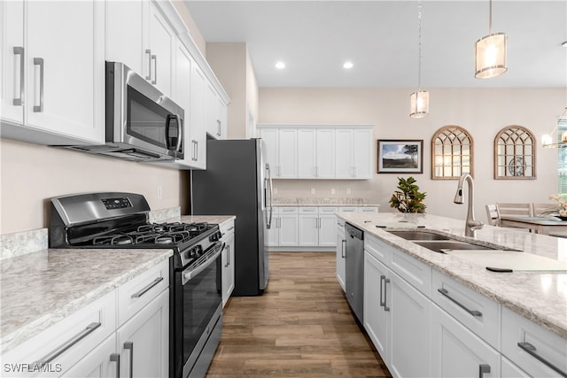 kitchen featuring white cabinets, dark hardwood / wood-style flooring, stainless steel appliances, decorative light fixtures, and sink