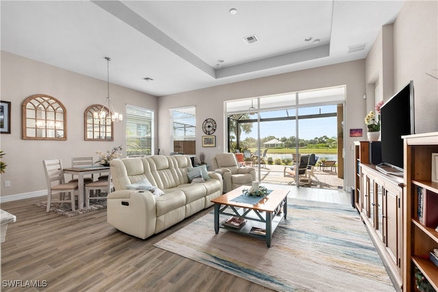 living room with an inviting chandelier, a healthy amount of sunlight, and hardwood / wood-style floors