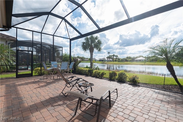 view of patio with a lanai and a water view