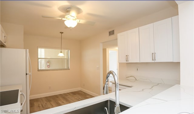 kitchen with white cabinets, stove, decorative light fixtures, hardwood / wood-style flooring, and light stone countertops