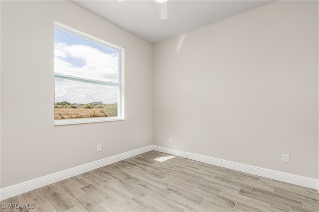 spare room featuring a ceiling fan, baseboards, and light wood finished floors