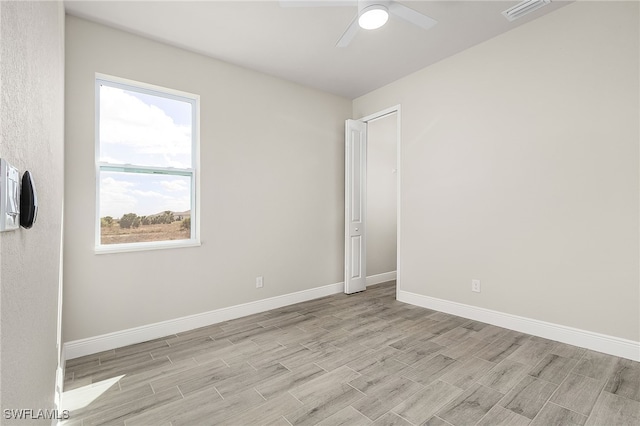 unfurnished room featuring baseboards, visible vents, light wood-type flooring, and a ceiling fan