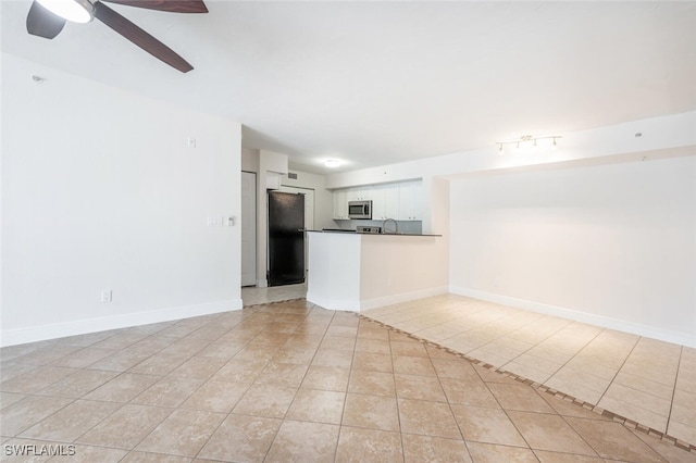 unfurnished living room featuring ceiling fan, sink, and light tile patterned floors