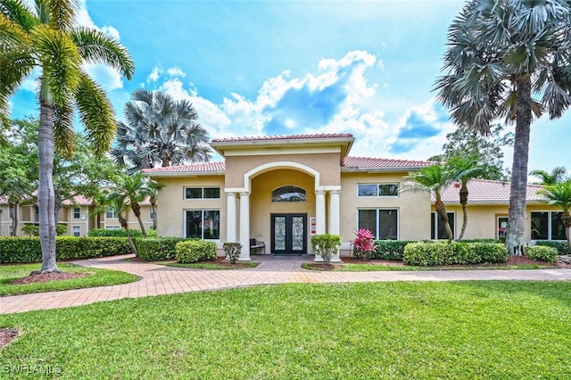 mediterranean / spanish-style house with a front lawn and french doors