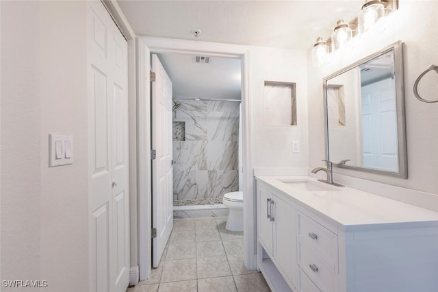 bathroom featuring tiled shower, tile patterned floors, vanity, and toilet