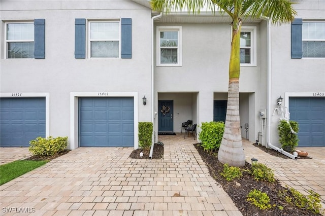 multi unit property featuring driveway, stucco siding, and a garage