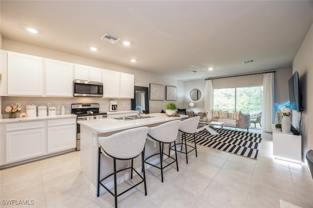 kitchen featuring white cabinets, sink, a kitchen island with sink, stainless steel appliances, and a kitchen breakfast bar