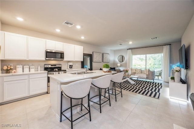 kitchen featuring a breakfast bar area, visible vents, a sink, white cabinetry, and appliances with stainless steel finishes