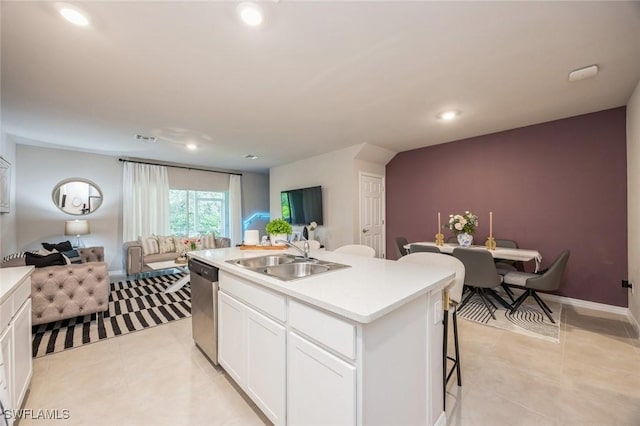 kitchen with a sink, open floor plan, white cabinetry, stainless steel dishwasher, and light countertops