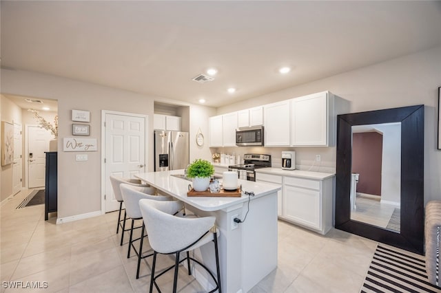 kitchen featuring a center island, stainless steel appliances, white cabinets, light tile patterned flooring, and a breakfast bar area