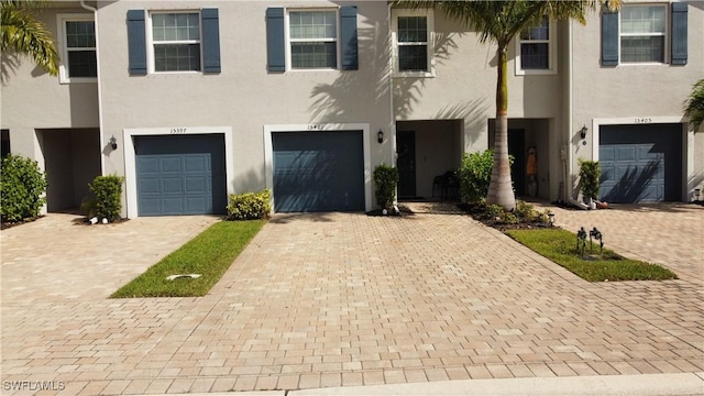 townhome / multi-family property with driveway, stucco siding, and a garage