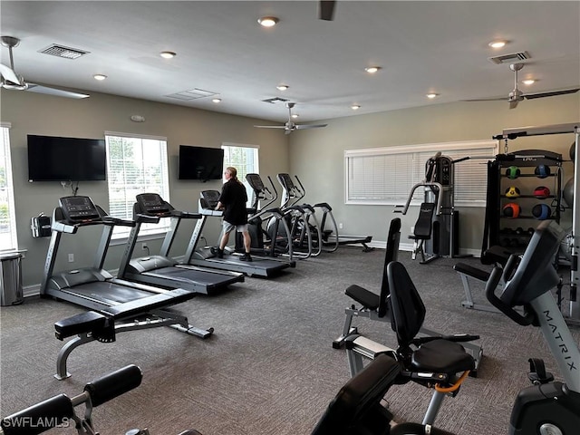 gym featuring baseboards, ceiling fan, and visible vents