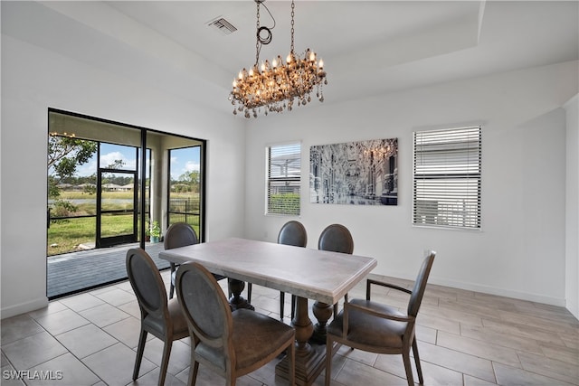 dining room with an inviting chandelier, light wood-type flooring, and a raised ceiling