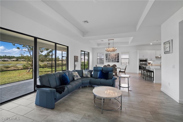 living room with a notable chandelier and a raised ceiling