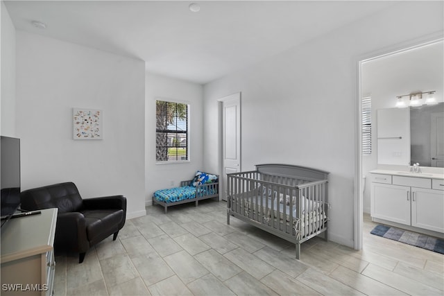 bedroom featuring sink, a crib, and ensuite bath