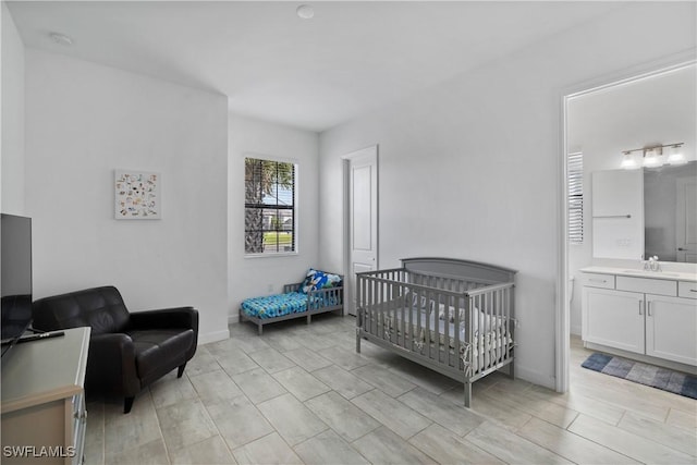 bedroom featuring a sink, connected bathroom, and baseboards