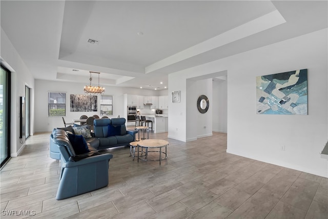 living room featuring light hardwood / wood-style floors, a tray ceiling, and a chandelier