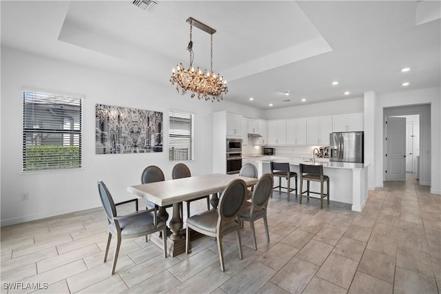 dining space with recessed lighting, a raised ceiling, visible vents, and an inviting chandelier