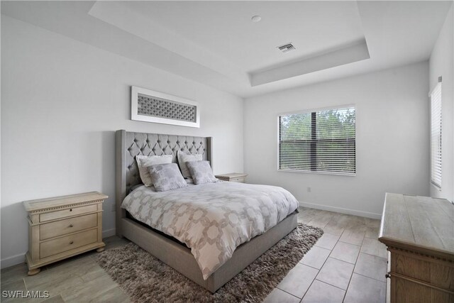 bedroom with a tray ceiling and baseboards