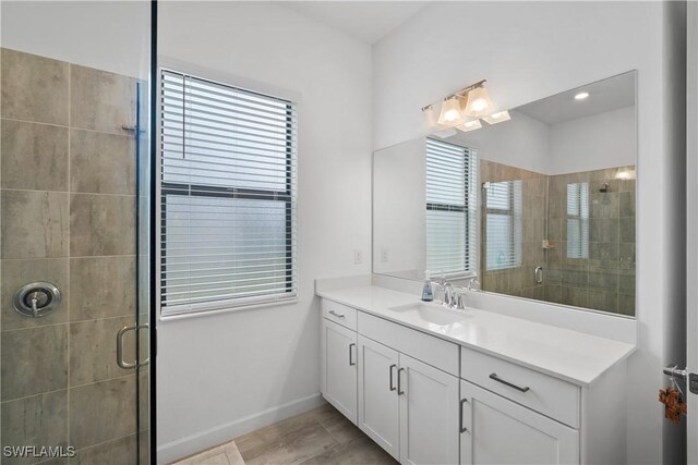 full bathroom with a stall shower, vanity, and baseboards