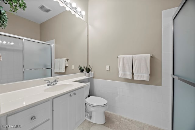 bathroom with tile patterned floors, an enclosed shower, toilet, vanity, and tile walls