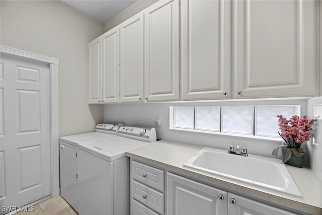 washroom with cabinets, light tile patterned floors, separate washer and dryer, and sink