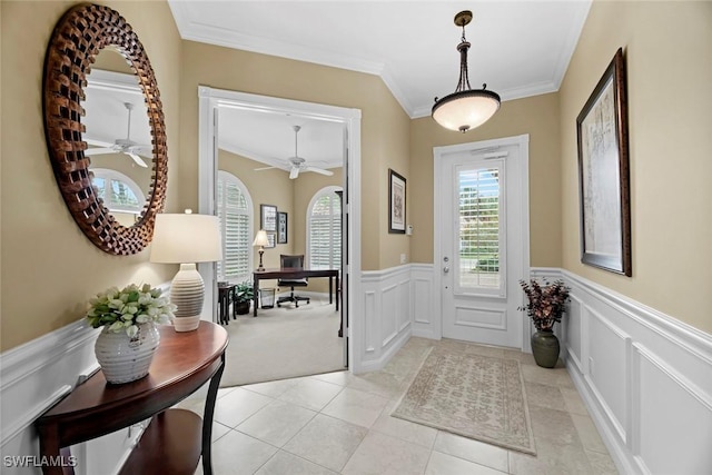 carpeted foyer entrance with crown molding and ceiling fan