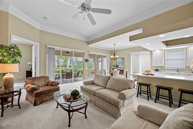 living room with ceiling fan with notable chandelier, light colored carpet, and crown molding