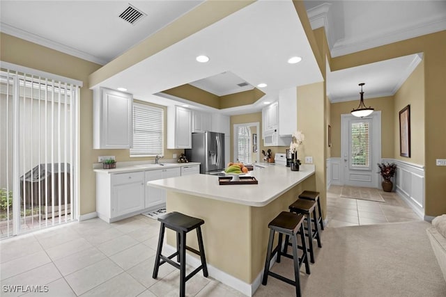 kitchen with white cabinetry, a kitchen breakfast bar, stainless steel refrigerator with ice dispenser, kitchen peninsula, and crown molding