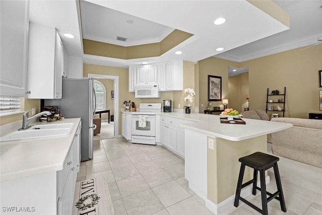 kitchen featuring a breakfast bar area, kitchen peninsula, white cabinetry, and white appliances