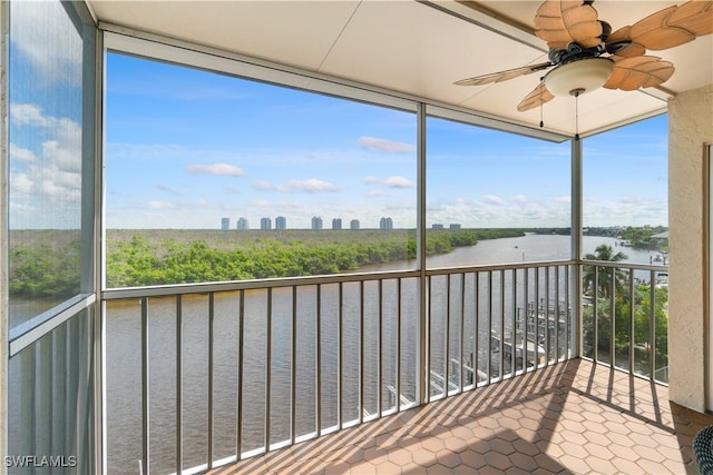 unfurnished sunroom featuring ceiling fan and a water view