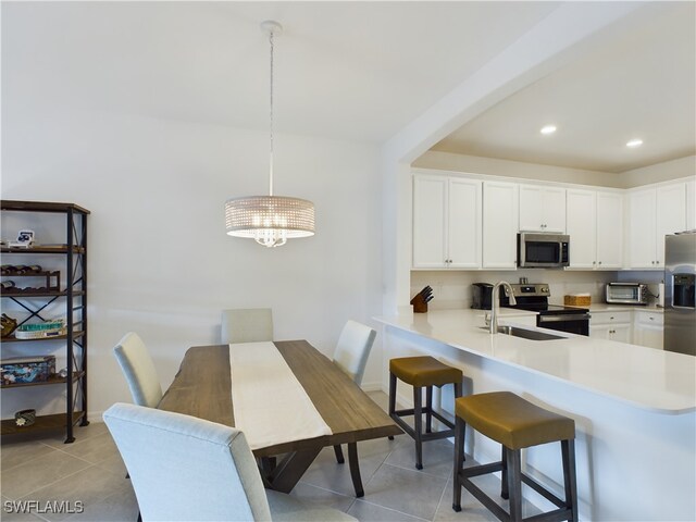 kitchen with white cabinets, stainless steel appliances, sink, hanging light fixtures, and kitchen peninsula