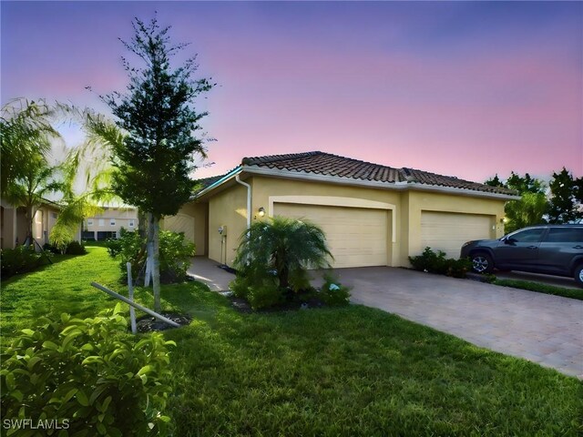 property exterior at dusk featuring a yard and a garage