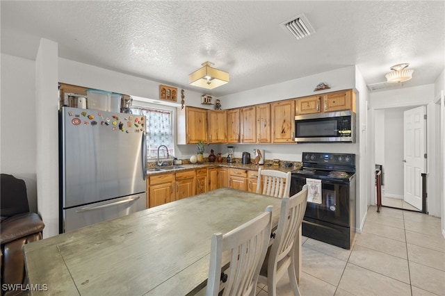 kitchen with light tile patterned floors, sink, stainless steel appliances, and a textured ceiling