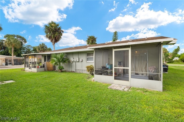 rear view of house with a sunroom and a yard