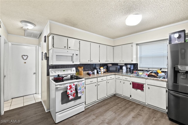 kitchen with a textured ceiling, wood-type flooring, white appliances, white cabinetry, and backsplash