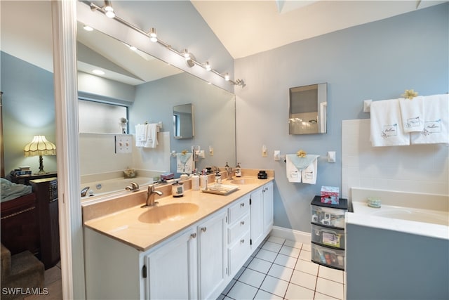 bathroom with vaulted ceiling, a washtub, vanity, and tile patterned floors