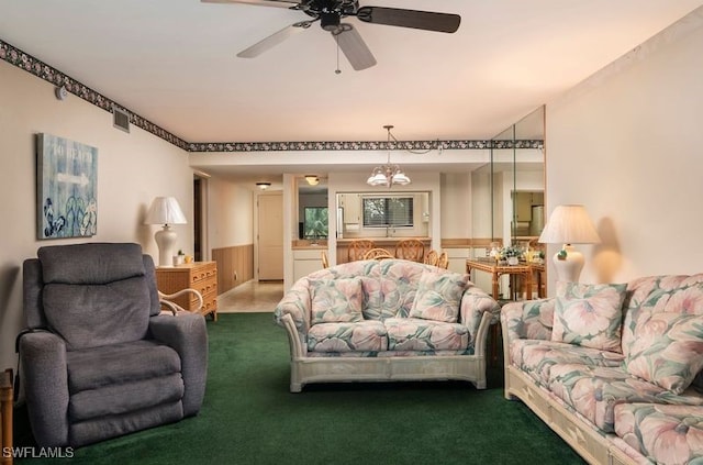 living room featuring carpet floors, ceiling fan with notable chandelier, and wooden walls