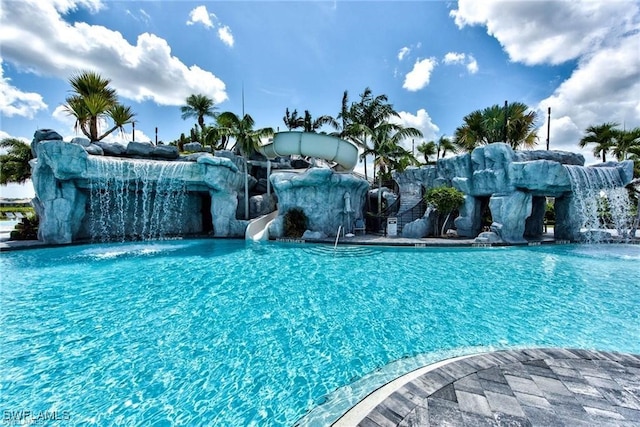 view of swimming pool with pool water feature and a water slide