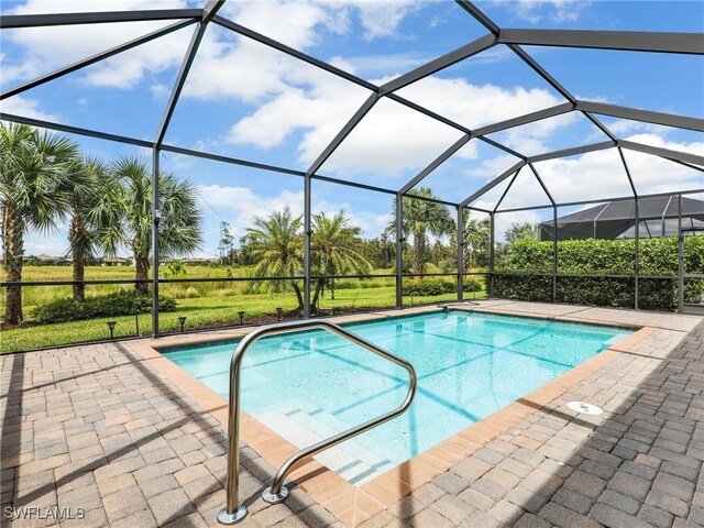 view of swimming pool with glass enclosure and a patio